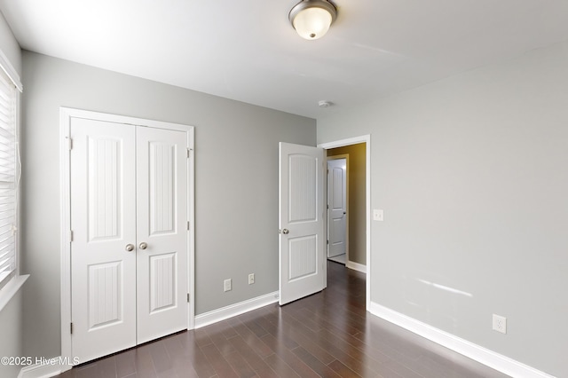 unfurnished bedroom with dark hardwood / wood-style flooring and a closet