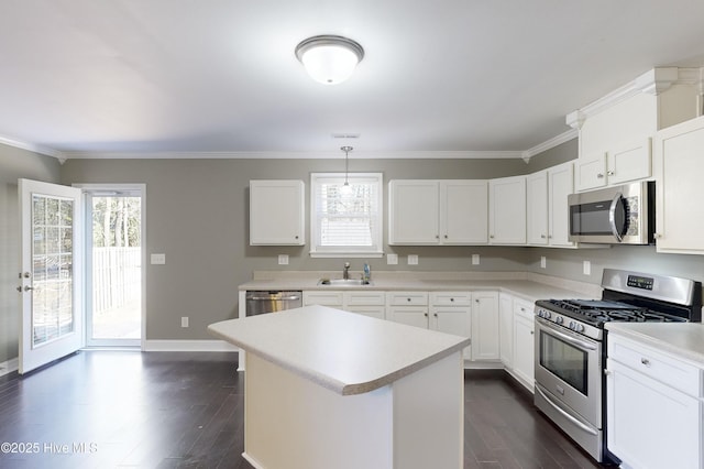 kitchen with pendant lighting, sink, appliances with stainless steel finishes, white cabinetry, and a center island