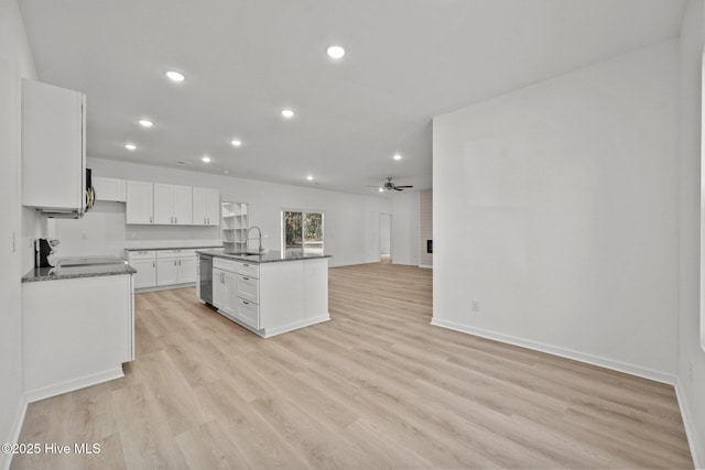 kitchen with sink, a kitchen island with sink, stainless steel appliances, light hardwood / wood-style floors, and white cabinets