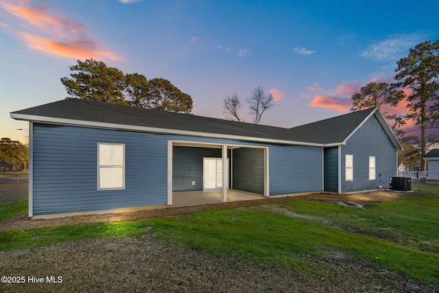 view of front of house with central AC, a yard, and a patio