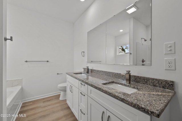 bathroom featuring wood-type flooring, toilet, a bath, and vanity