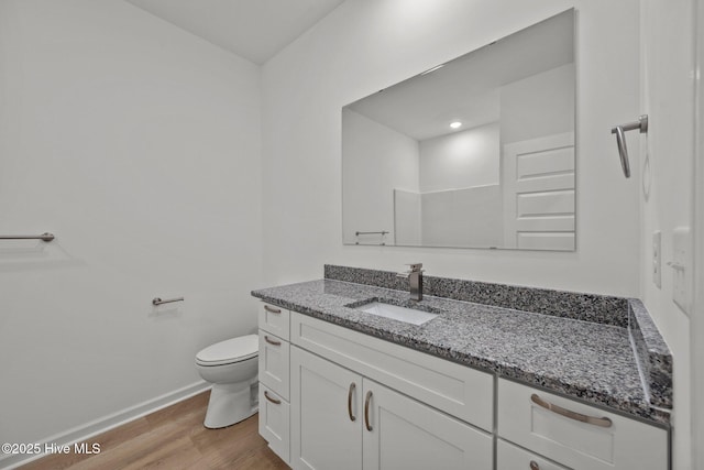 bathroom featuring wood-type flooring, toilet, and vanity