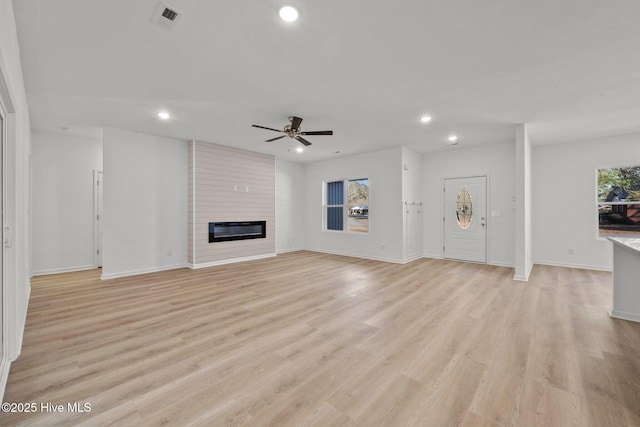 unfurnished living room with ceiling fan, a fireplace, and light hardwood / wood-style flooring