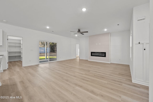 unfurnished living room featuring ceiling fan, a fireplace, and light wood-type flooring