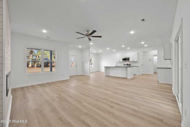 unfurnished living room with sink, light hardwood / wood-style flooring, and ceiling fan