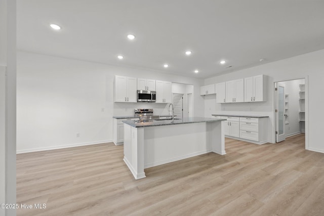 kitchen with a center island with sink, white cabinets, and appliances with stainless steel finishes