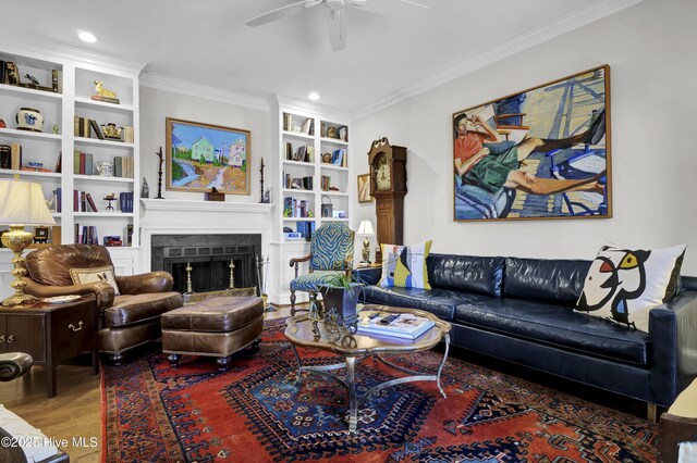 sitting room with hardwood / wood-style flooring, crown molding, and built in shelves