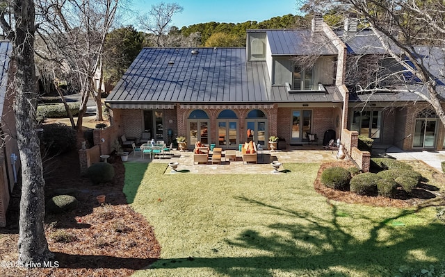 back of property with an outdoor living space with a fire pit, a patio, and a lawn