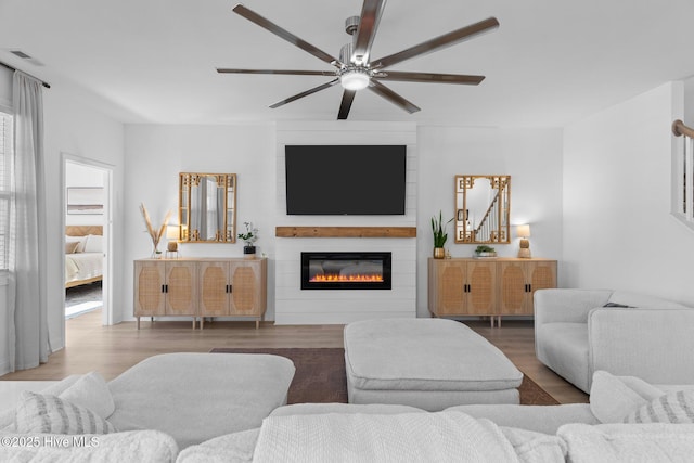 living room with hardwood / wood-style flooring, ceiling fan, and a fireplace