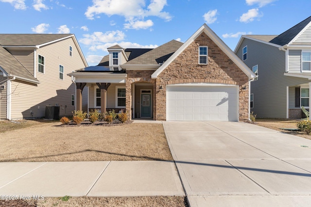 view of front of home featuring a garage, central AC unit, covered porch, and solar panels