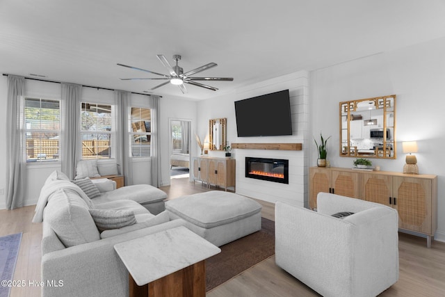 living room featuring ceiling fan, light hardwood / wood-style floors, and a wealth of natural light