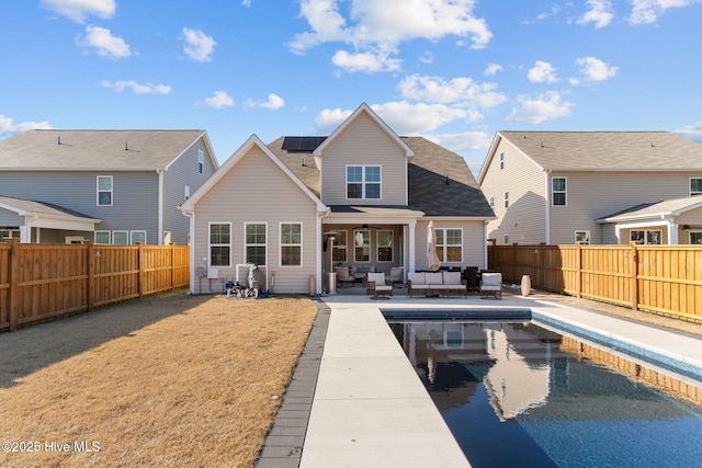 rear view of house featuring an outdoor living space, a yard, a patio area, and a fenced in pool