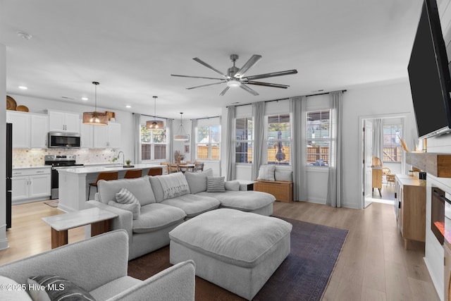 living room featuring ceiling fan, a healthy amount of sunlight, and light hardwood / wood-style floors