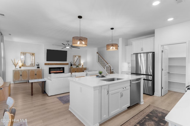 kitchen featuring sink, white cabinetry, decorative light fixtures, a center island with sink, and appliances with stainless steel finishes