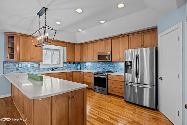 kitchen with vaulted ceiling, appliances with stainless steel finishes, a breakfast bar, decorative light fixtures, and kitchen peninsula