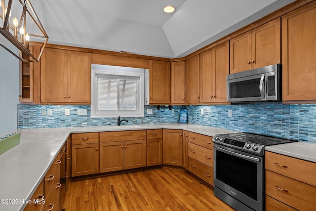 kitchen with tasteful backsplash, lofted ceiling, stainless steel appliances, and light hardwood / wood-style floors