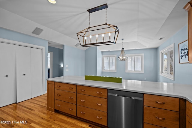 kitchen with stainless steel dishwasher, decorative light fixtures, a raised ceiling, and light hardwood / wood-style flooring