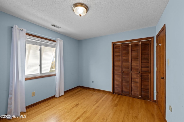 unfurnished bedroom featuring a textured ceiling, light wood-type flooring, and a closet