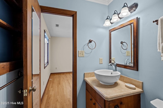 bathroom with vanity, wood-type flooring, crown molding, and toilet