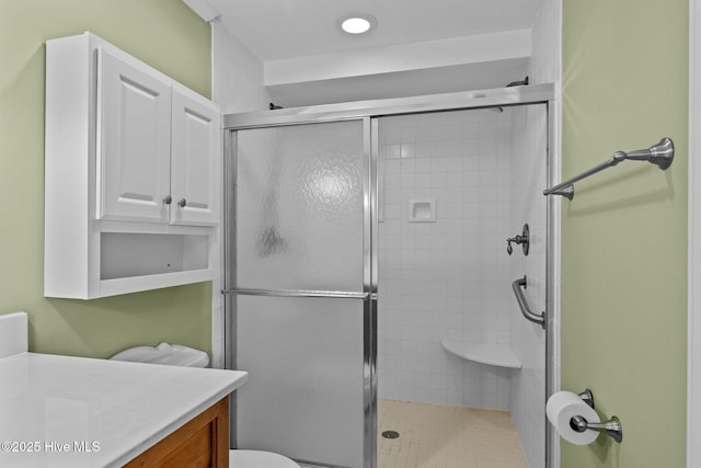 bathroom with vanity, a shower with door, and toilet