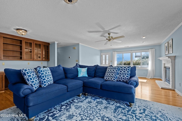 living room with ceiling fan, ornamental molding, wood-type flooring, and a textured ceiling