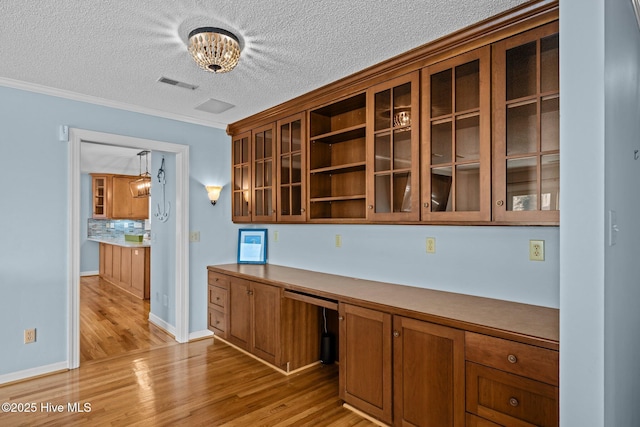 kitchen featuring built in desk, light hardwood / wood-style floors, hanging light fixtures, and a textured ceiling