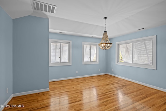 spare room with light hardwood / wood-style floors and a chandelier