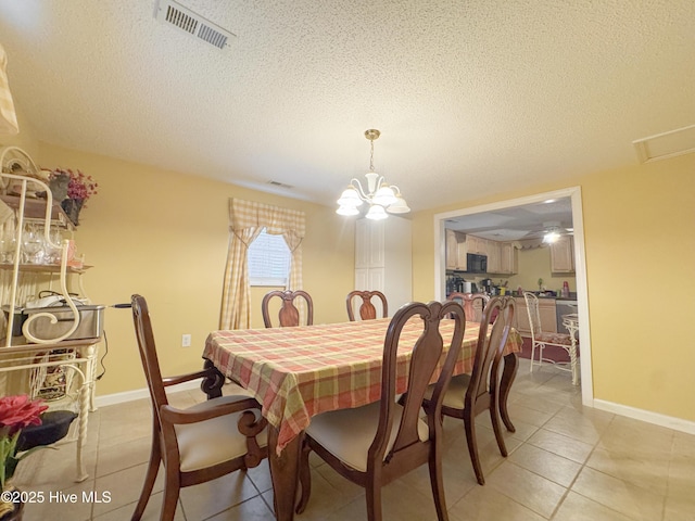 tiled dining area with a chandelier and a textured ceiling