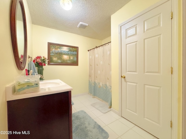 bathroom featuring tile patterned flooring, vanity, and a textured ceiling