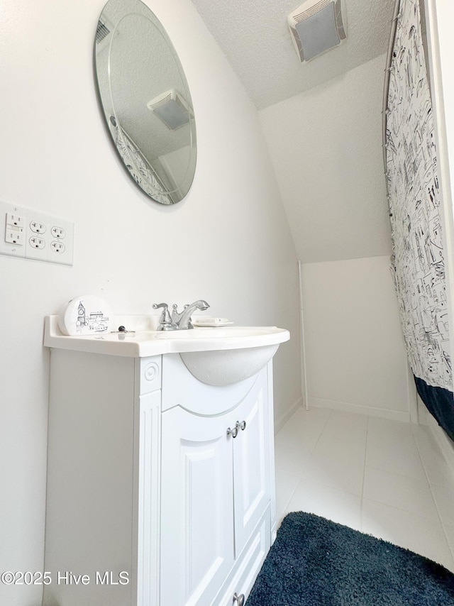 bathroom with vanity, tile patterned flooring, vaulted ceiling, and a textured ceiling