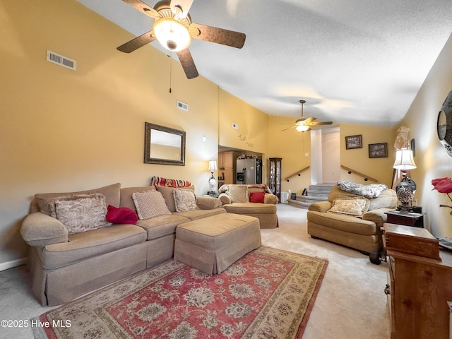 carpeted living room with ceiling fan, high vaulted ceiling, and a textured ceiling