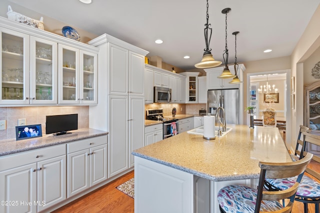 kitchen featuring appliances with stainless steel finishes, a center island with sink, and white cabinets