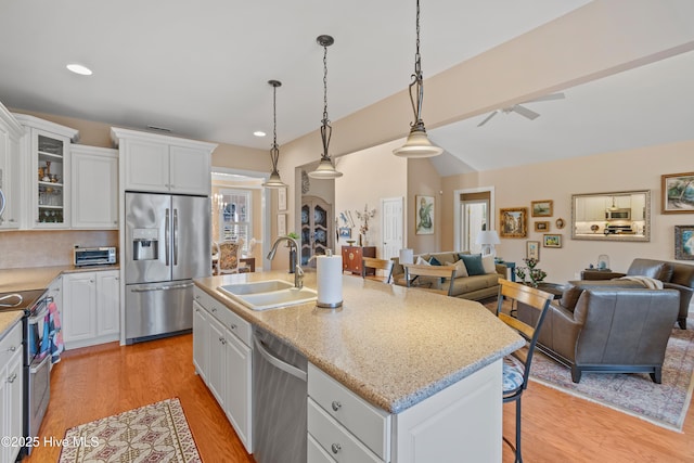 kitchen with sink, hanging light fixtures, appliances with stainless steel finishes, an island with sink, and white cabinets