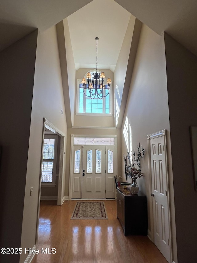 foyer entrance featuring an inviting chandelier, hardwood / wood-style floors, and a towering ceiling