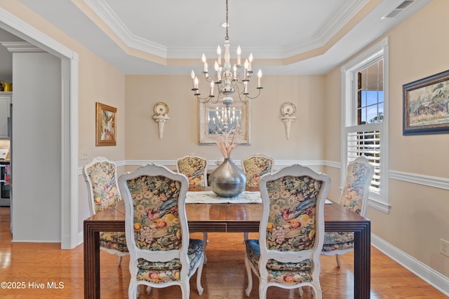 dining space with hardwood / wood-style floors, an inviting chandelier, and a tray ceiling