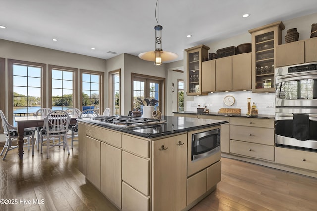 kitchen featuring a kitchen island, wood-type flooring, hanging light fixtures, stainless steel appliances, and a water view