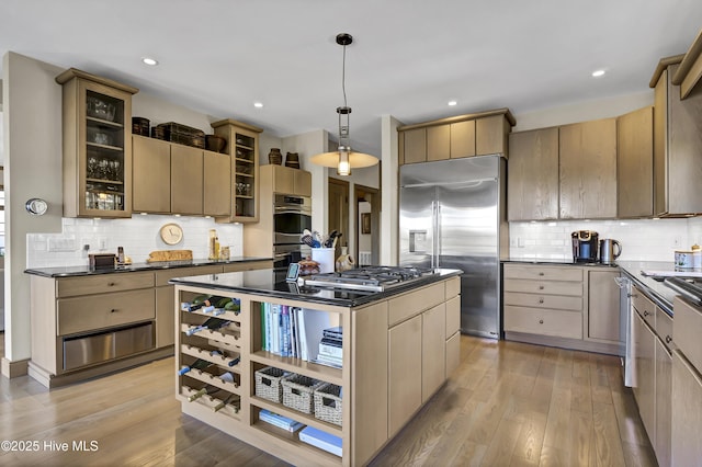 kitchen featuring light brown cabinetry, light hardwood / wood-style flooring, a kitchen island, pendant lighting, and stainless steel appliances