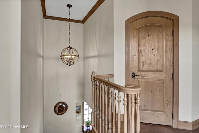 staircase with hardwood / wood-style flooring, ornamental molding, and a chandelier