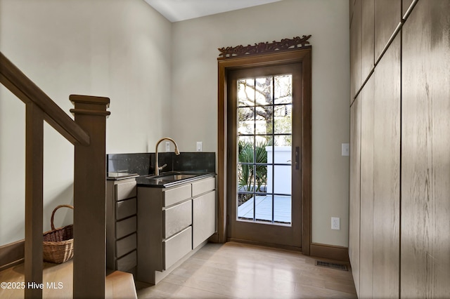 doorway to outside with sink and light wood-type flooring