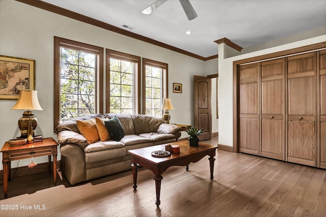 living room featuring crown molding, ceiling fan, and light wood-type flooring