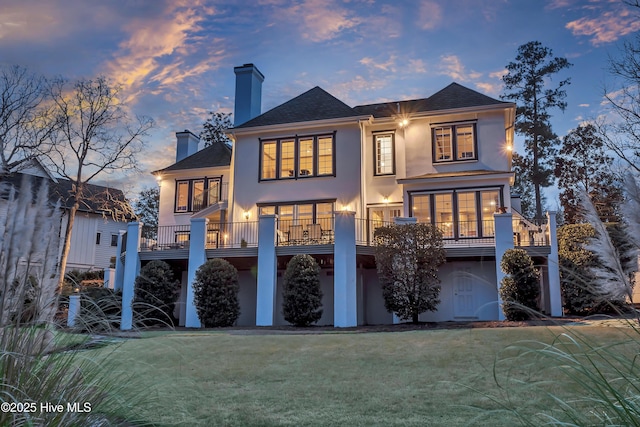 back house at dusk with a lawn