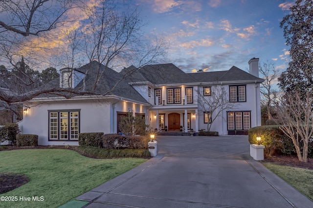 view of front of property featuring french doors, a balcony, and a lawn