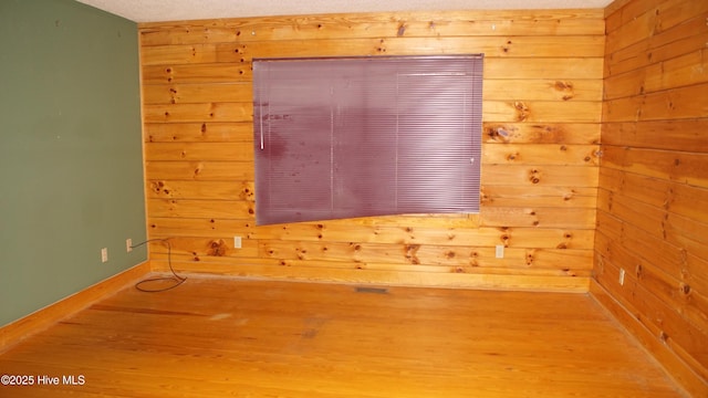 spare room featuring hardwood / wood-style floors, a textured ceiling, and wooden walls