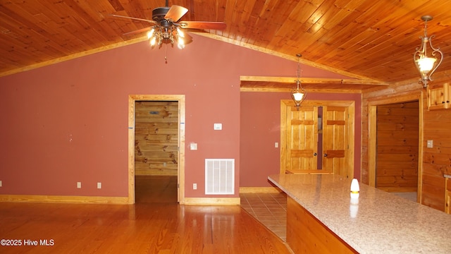 kitchen featuring hanging light fixtures, vaulted ceiling, light stone countertops, and wood-type flooring