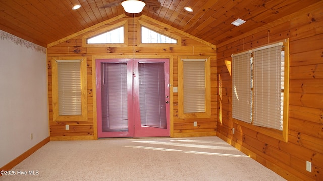 carpeted spare room featuring lofted ceiling, wood ceiling, and wooden walls