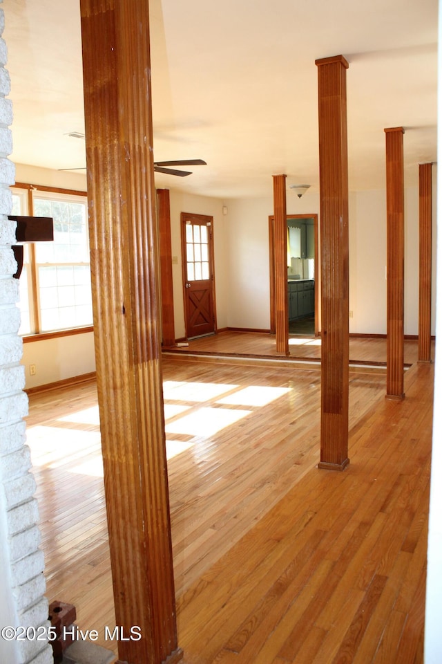 unfurnished room with hardwood / wood-style floors and decorative columns