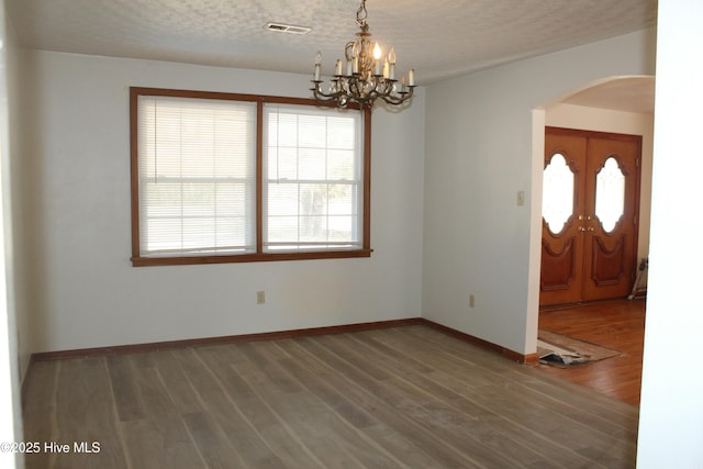 spare room with hardwood / wood-style floors, a notable chandelier, and a textured ceiling