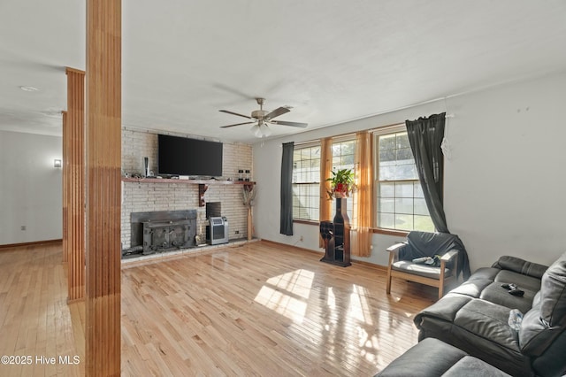 living room with a fireplace, light hardwood / wood-style floors, and ceiling fan