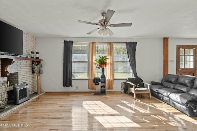 living room with ceiling fan, light hardwood / wood-style floors, and a wood stove