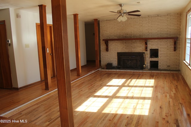 unfurnished living room with hardwood / wood-style floors, a brick fireplace, and ceiling fan